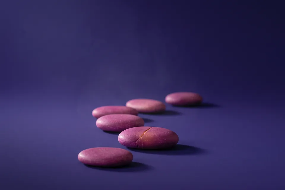 Camino curvo de piedras planas magenta y rosa sobre una superficie violeta.